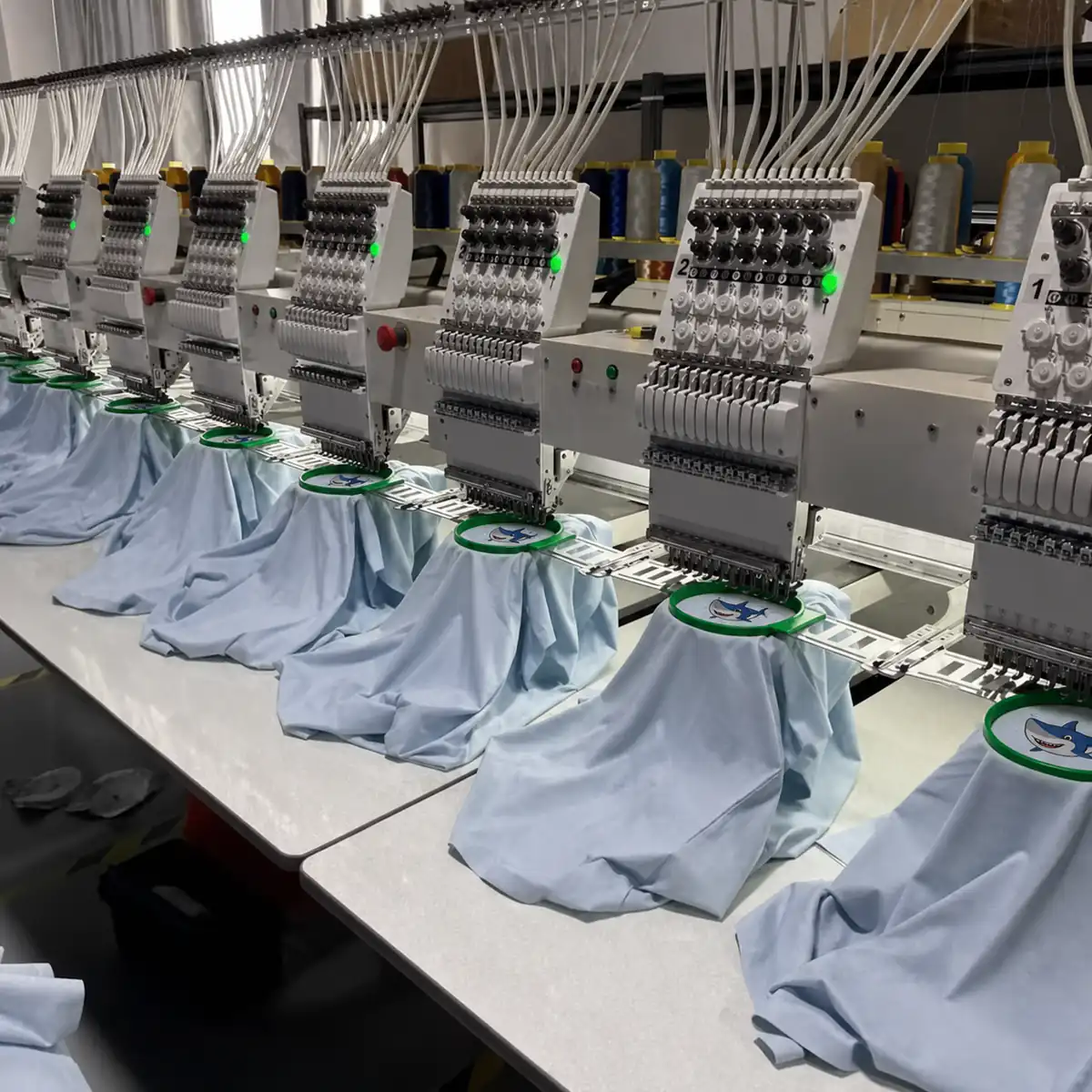 Anonymized multi-head embroidery line producing shark motifs
