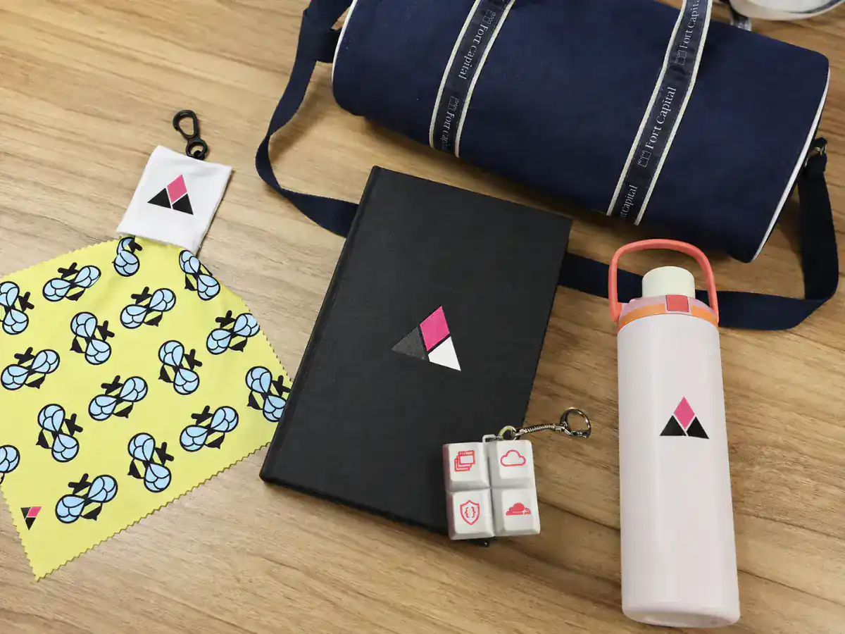 Anonymized corporate anniversary gift collection with notebook, travel bag, bottle, keychain and screen cleaner