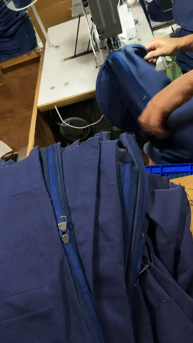Anonymized production of navy travel bags at a sewing workstation