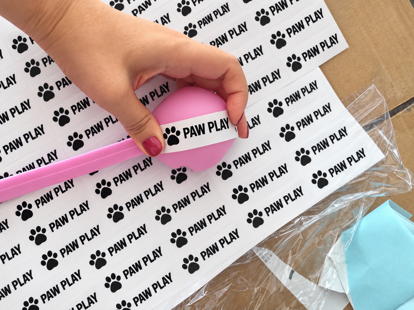 Second view of anonymized logo sticker positioning on a pink dog ball launcher